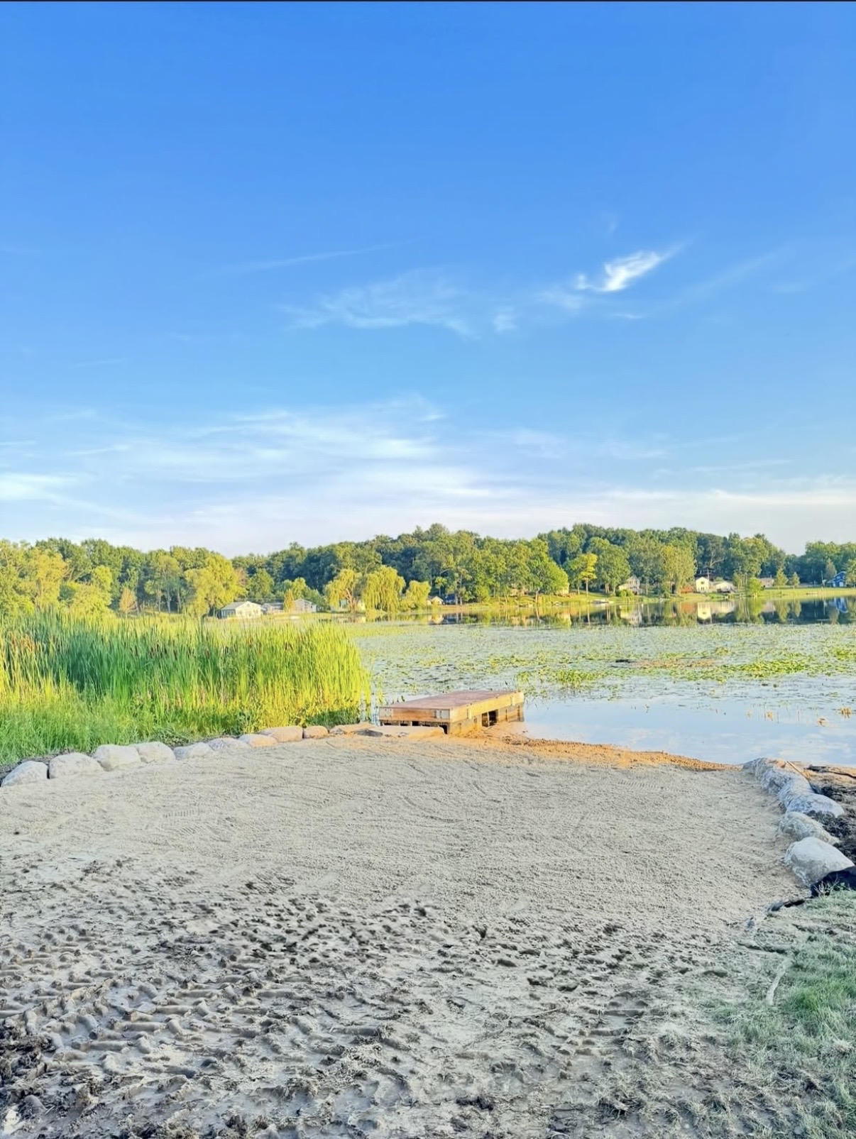 Finished sand beach with rock border and dock after shoreline restoration