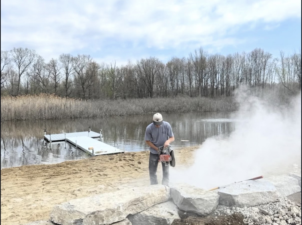 Crew member cutting stone on site during a seawall project
