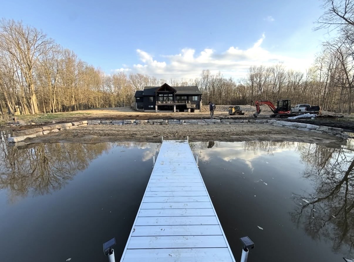 Seawall installation in progress with excavator and dock